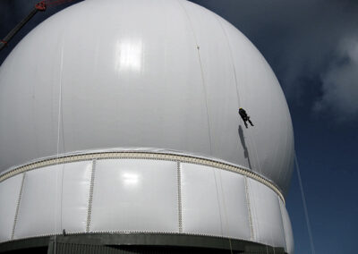 Inspecting a large air supported radome from ropes.